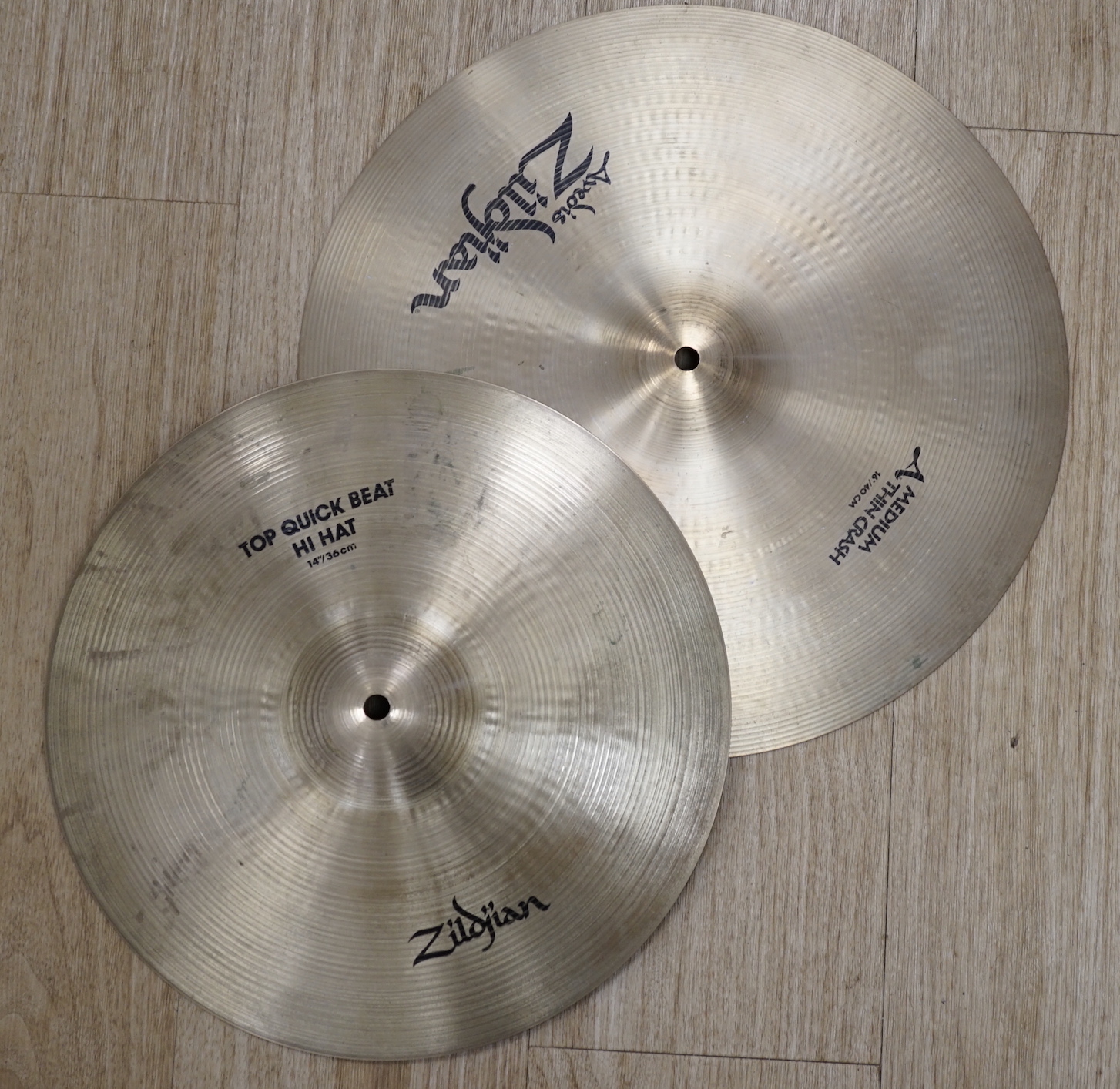 Four Zildjian drum kit cymbals; a 14” Top Quick Beat Hi-hat pair, a 16” Medium Thin Crash, an 18” Thin Crash and a 20” Ride Cymbal, within two cases